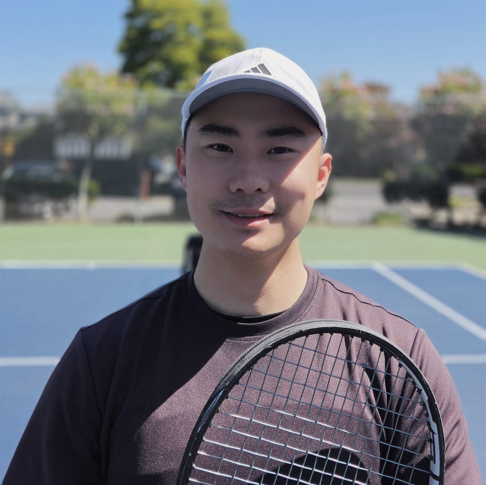 Albert, founder and coach of SwingOn, on a tennis court holding a racket